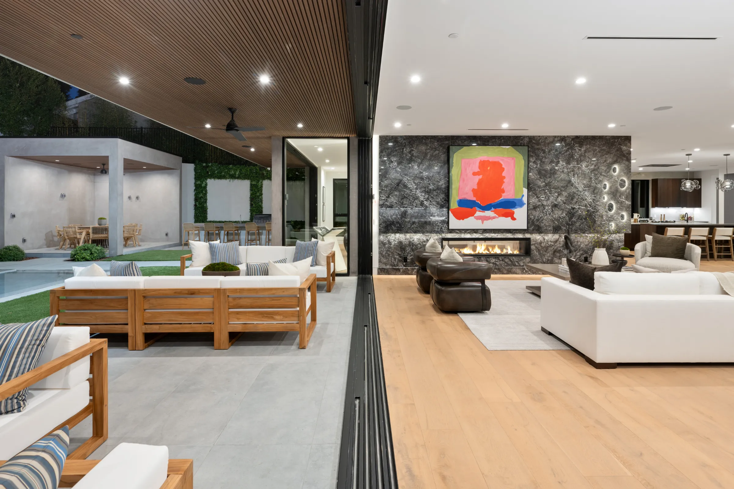 After full-home remodeling project in Los Angeles with open indoor-outdoor living, modern fireplace wall, updated flooring, improved kitchen connection, recessed lighting, and cohesive interior finishes