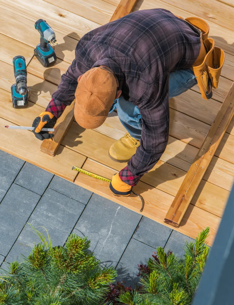 Los Angeles backyard remodeling project with wood deck installation, patio construction, outdoor flooring, and contractor measuring decking boards